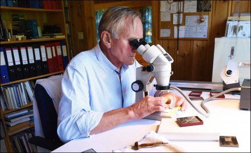Sverre Morken en su estudio grabando un sello con microscopio binocular